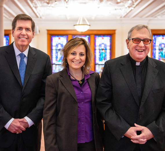 A man with a beard and tattooed arms stands with his arms crossed